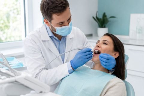 Dentist in a mask and blue gloves placing a tooth-colored filling for a relaxed patient during a dental filling appointment in Whittier CA